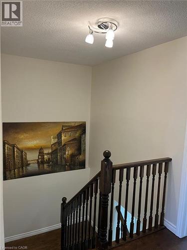 Hardwood stairs with a dark wood banister and spindles, illuminated by a chrome track light fixture - 1367 Upper Paradise Road, Hamilton, ON - Indoor Photo Showing Other Room
