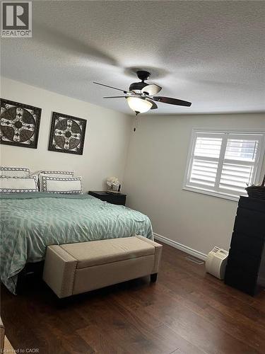 Wood-finish flooring throughout, featuring a ceiling fan with integrated lighting, and a window with white plantation shutters - 1367 Upper Paradise Road, Hamilton, ON - Indoor Photo Showing Bedroom
