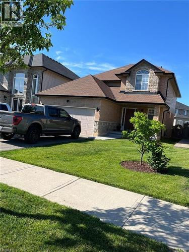Two-story residence featuring a brick and siding exterior, an attached garage, a gabled roofline with asphalt shingles, a manicured front lawn, and a sidewalk - 1367 Upper Paradise Road, Hamilton, ON - Outdoor