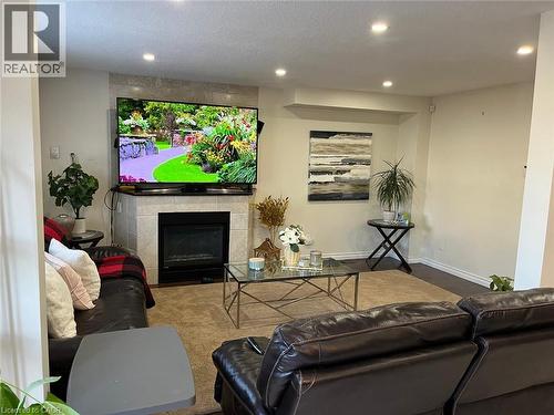 Living area featuring a tiled fireplace with an integrated media shelf, recessed ceiling lights, and dark wood-finish flooring - 1367 Upper Paradise Road, Hamilton, ON - Indoor Photo Showing Other Room With Fireplace