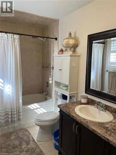 Bathroom featuring a tiled shower surround, white tub, dark wood-finish vanity with an integrated sink, and a large framed mirror - 1367 Upper Paradise Road, Hamilton, ON - Indoor Photo Showing Bathroom