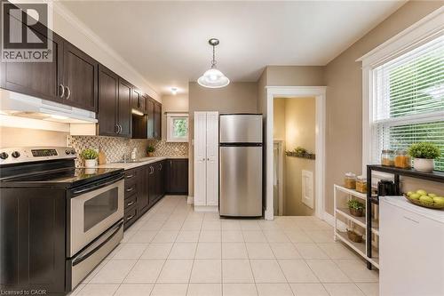 Kitchen featuring dark wood-finish cabinetry, stainless steel appliances, and light tile flooring - 74 Royal Avenue, Hamilton, ON - Indoor Photo Showing Kitchen