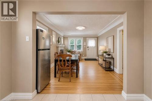 Stainless steel refrigerator positioned within an arched doorway, opening into a dining area with wood-finish flooring - 74 Royal Avenue, Hamilton, ON - Indoor