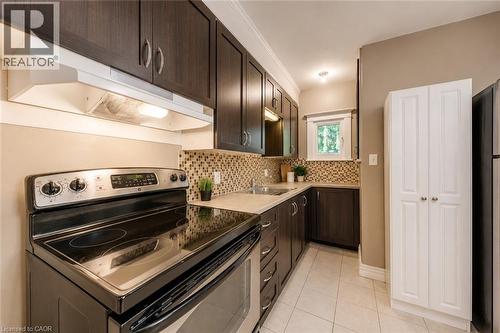 Functional kitchen featuring dark wood-finish cabinetry, tile backsplash, and light-toned countertops - 74 Royal Avenue, Hamilton, ON - Indoor Photo Showing Kitchen