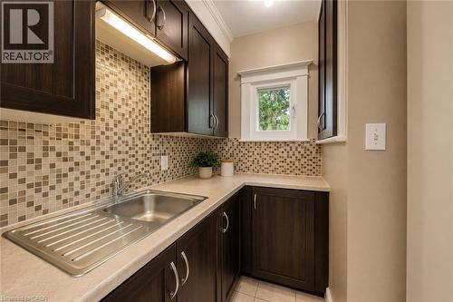Kitchen area featuring dark wood-finish cabinetry, a mosaic tile backsplash, and light-toned countertops - 74 Royal Avenue, Hamilton, ON - Indoor Photo Showing Kitchen