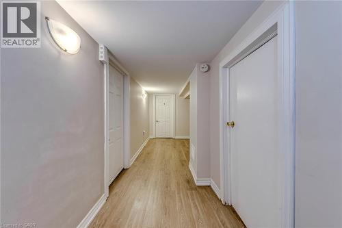 Hallway featuring wood-finish flooring, white doors, and contemporary wall sconces - 74 Royal Avenue, Hamilton, ON - Indoor Photo Showing Other Room