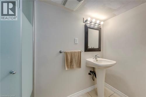 Bathroom featuring a pedestal sink, framed mirror, and a frosted glass shower enclosure - 74 Royal Avenue, Hamilton, ON - Indoor Photo Showing Bathroom