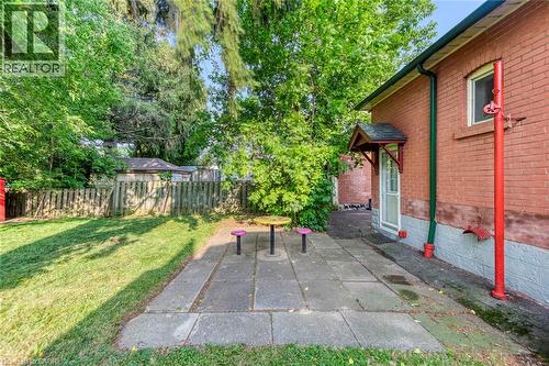 Expansive backyard featuring a stone patio, a red brick exterior, and a wooden privacy fence - 74 Royal Avenue, Hamilton, ON - Outdoor