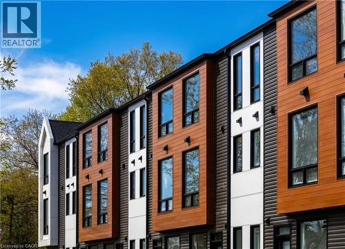Modern townhome exteriors featuring wood-finish siding, dark horizontal paneling, and white vertical accents - 210 Heritage Drive Unit# Main, Kitchener, ON - Outdoor