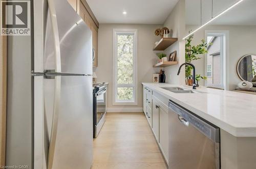 Modern kitchen featuring stainless steel appliances, light wood-finish flooring, white countertops, a black gooseneck faucet, and open wood shelving - 210 Heritage Drive Unit# Main, Kitchener, ON - Indoor Photo Showing Kitchen With Double Sink
