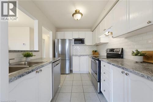 Well-appointed kitchen featuring white cabinetry, subway tile backsplash, stainless steel appliances, granite-style countertops, and tile flooring - 4425 Peter Drive, Burlington, ON - Indoor Photo Showing Kitchen With Double Sink With Upgraded Kitchen