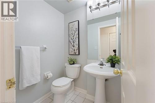 Pedestal sink with chrome faucet, white toilet, and tile flooring - 4425 Peter Drive, Burlington, ON - Indoor Photo Showing Bathroom