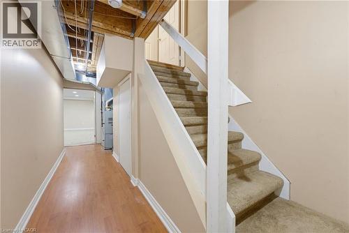 Carpeted staircase with white painted stringers, complemented by a wood-finish floor hallway featuring neutral painted walls and exposed ductwork - 4425 Peter Drive, Burlington, ON - Indoor Photo Showing Other Room