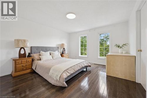 Spacious interior featuring dark wood-finish flooring, white walls, dual windows, and a flush-mount ceiling light - 600 White Elm Boulevard Unit# 9, Waterloo, ON - Indoor Photo Showing Bedroom
