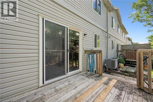 Ground-level wood deck with a sliding glass door entry to the property, featuring light-colored horizontal siding and multiple windows - 600 White Elm Boulevard Unit# 9, Waterloo, ON - Outdoor With Deck Patio Veranda With Exterior