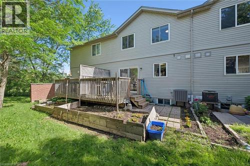 Rear exterior featuring a multi-level wood deck, ground-level patio, and wood-sided raised garden beds - 600 White Elm Boulevard Unit# 9, Waterloo, ON - Outdoor With Deck Patio Veranda With Exterior