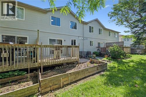 Rear exterior featuring horizontal siding, multiple sliding glass doors, and a wood deck with railings - 600 White Elm Boulevard Unit# 9, Waterloo, ON - Outdoor With Deck Patio Veranda