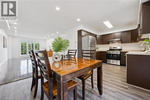 Open-concept kitchen and dining area featuring rich dark wood-finish cabinetry, stainless steel appliances, and wood-finish flooring - 600 White Elm Boulevard Unit# 9, Waterloo, ON - Indoor