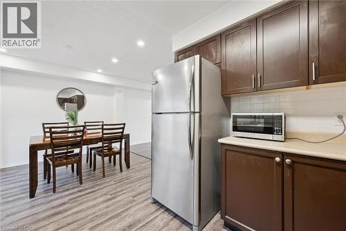 Kitchenette with stainless steel refrigerator, dark wood-finish cabinetry, and light-toned countertop - 600 White Elm Boulevard Unit# 9, Waterloo, ON - Indoor Photo Showing Other Room