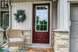 Entryway featuring a maroon paneled door with glass inserts, stone façade accents, vertical siding, and an overhead light fixture - 