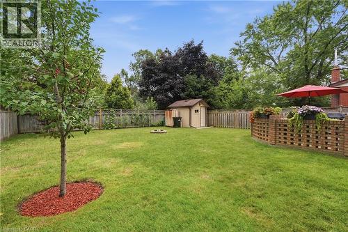 Expansive green lawn featuring a mature tree, a brick garden wall, and a storage shed - 76 Lower Canada Crescent, Kitchener, ON - Outdoor With Backyard