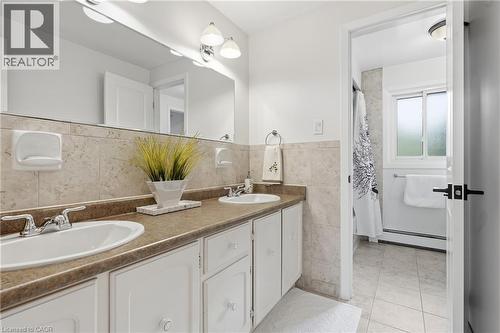 Bathroom vanity featuring dual undermount sinks with chrome fixtures, a laminate countertop, and white cabinetry - 76 Lower Canada Crescent, Kitchener, ON - Indoor Photo Showing Bathroom