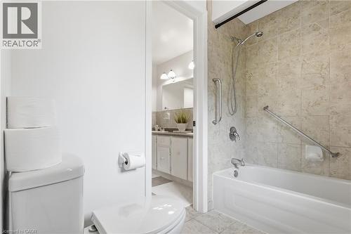 Full bathroom featuring a white bathtub with tile surround, a chrome showerhead, and grab bars - 76 Lower Canada Crescent, Kitchener, ON - Indoor Photo Showing Bathroom