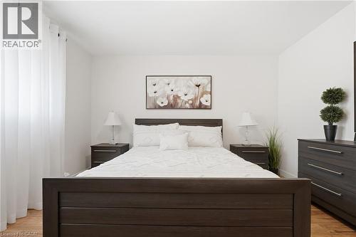 Bright bedroom featuring light wood-finish flooring, white walls, and a large window with sheer white curtains - 76 Lower Canada Crescent, Kitchener, ON - Indoor Photo Showing Bedroom
