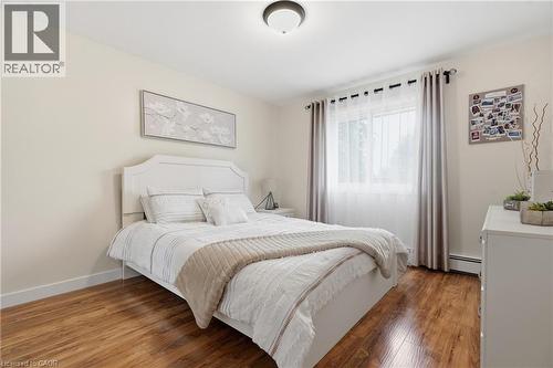 Light-filled room featuring wood-finish flooring, a window with sheer and blackout curtains, and a ceiling-mounted light fixture - 76 Lower Canada Crescent, Kitchener, ON - Indoor Photo Showing Bedroom