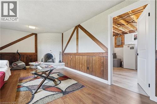 Recreational room featuring wood-finish flooring, white brick fireplace, wood wall paneling, and exposed wood beams - 76 Lower Canada Crescent, Kitchener, ON - Indoor