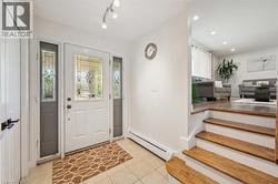 Entryway featuring a decorative glass front door with sidelights, ceramic tile flooring, and track lighting - 