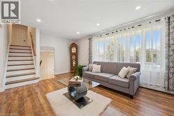 Living space featuring wood-finish flooring, recessed lighting, and a prominent staircase with wood treads and handrail - 