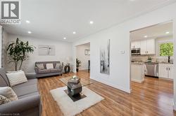 Open-concept living area with wood-finish flooring, recessed lighting, and white baseboards - 