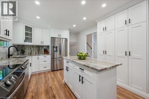 Contemporary kitchen featuring white cabinetry with black hardware, stainless steel appliances, wood-finish flooring, a central island with countertop, and recessed lighting - 76 Lower Canada Crescent, Kitchener, ON - Indoor Photo Showing Kitchen With Upgraded Kitchen