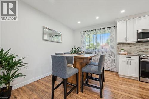 Open-concept kitchen and dining area featuring wood-finish flooring, recessed lighting, and white cabinetry with dark hardware - 76 Lower Canada Crescent, Kitchener, ON - Indoor