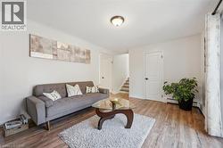 Living area featuring wood-finish flooring, white walls, and a ceiling-mounted light fixture - 