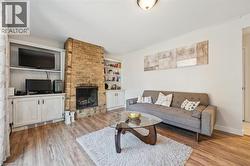 Living area featuring a brick fireplace, wood-finish flooring, and built-in cabinetry - 