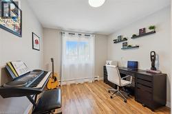 Light-filled interior space featuring wood-finish flooring, a window with sheer white curtains, and a built-in wall-mounted shelving system - 