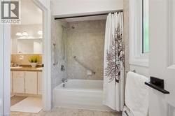 Tub and shower combination featuring neutral-toned tile surround and chrome fixtures - 