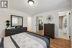 Bedroom featuring wood-finish flooring, a flush-mount ceiling light, and white walls - 
