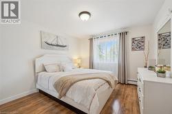 Wood-finish flooring throughout, bright white walls, and a window with sheer and blackout curtains - 