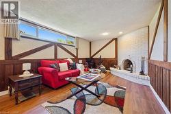 Living area featuring wood-finish flooring, a white brick fireplace with a hearth, and exposed wood beams - 