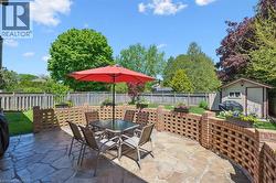 Flagstone patio featuring curved brick lattice walls with integrated planters, expansive lawn, and a storage shed - 