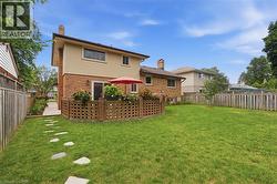 Expansive backyard featuring a brick patio, stone paver pathway, mature trees, and privacy fencing - 