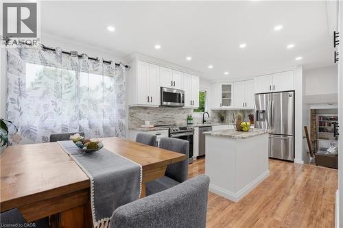 Modern kitchen featuring white cabinetry, stainless steel appliances, a light-toned backsplash, recessed lighting, and wood-finish flooring - 76 Lower Canada Crescent, Kitchener, ON - Indoor