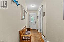 Entryway featuring a white door with an oval stained-glass insert, wood-finish flooring, and light-toned wall paint - 