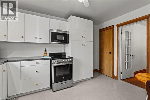 Kitchen featuring white cabinetry with gold-toned hardware, stainless steel oven/range, and an over-the-range microwave - 37 Park Row N, Hamilton, ON - Indoor Photo Showing Kitchen