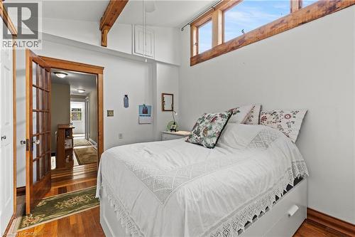 Hardwood flooring throughout featuring natural wood trim and a French pane door - 37 Park Row N, Hamilton, ON - Indoor Photo Showing Bedroom