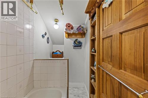 Bathtub with white tile surround, brass shower rod, and marble-finish flooring - 37 Park Row N, Hamilton, ON - Indoor Photo Showing Bathroom