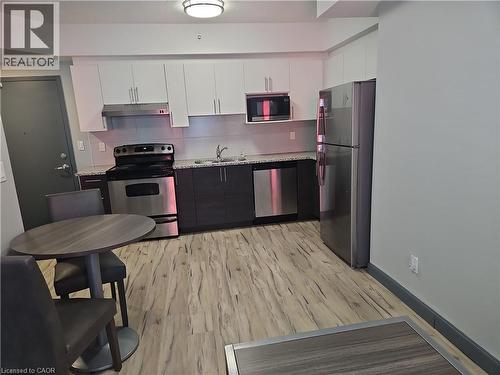 Kitchen with appliances with stainless steel finishes, light wood-style flooring, tasteful backsplash, white cabinets, and under cabinet range hood - 258B Sunview Street Unit# 255, Waterloo, ON - Indoor Photo Showing Kitchen With Stainless Steel Kitchen